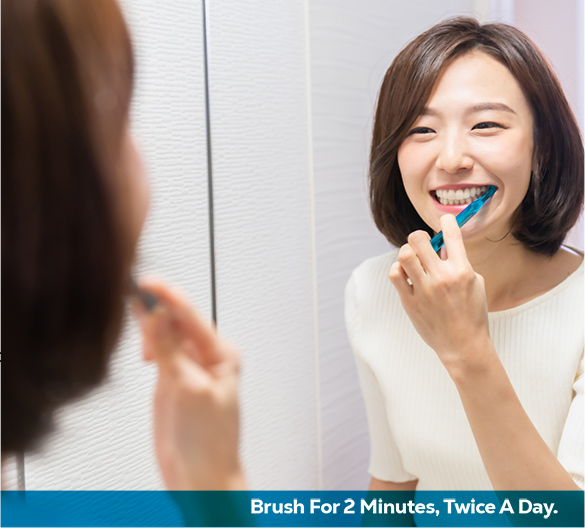 a woman brushing teeth looking in the mirror