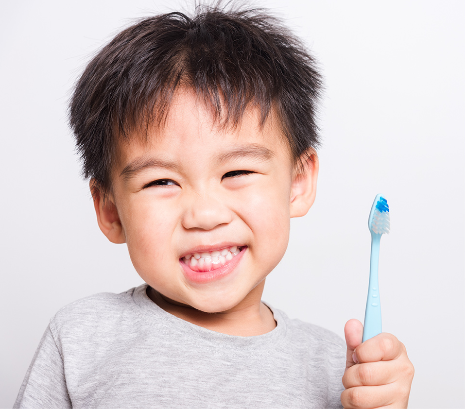 a cute kid smiling holding a toothbrush