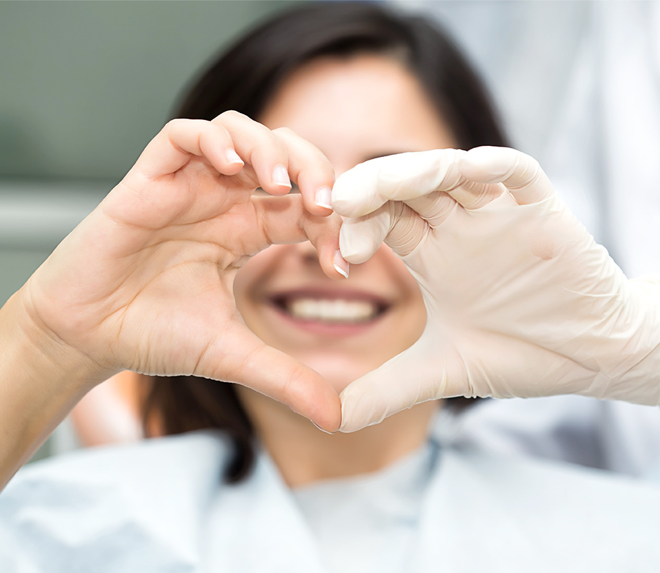 dentist smiling through heart-shaped hands.