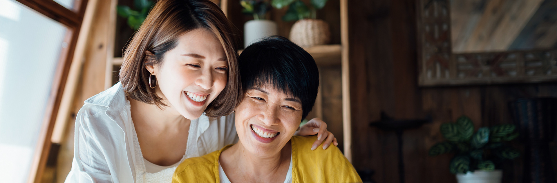 Happy young woman and elder woman smiling indoors.